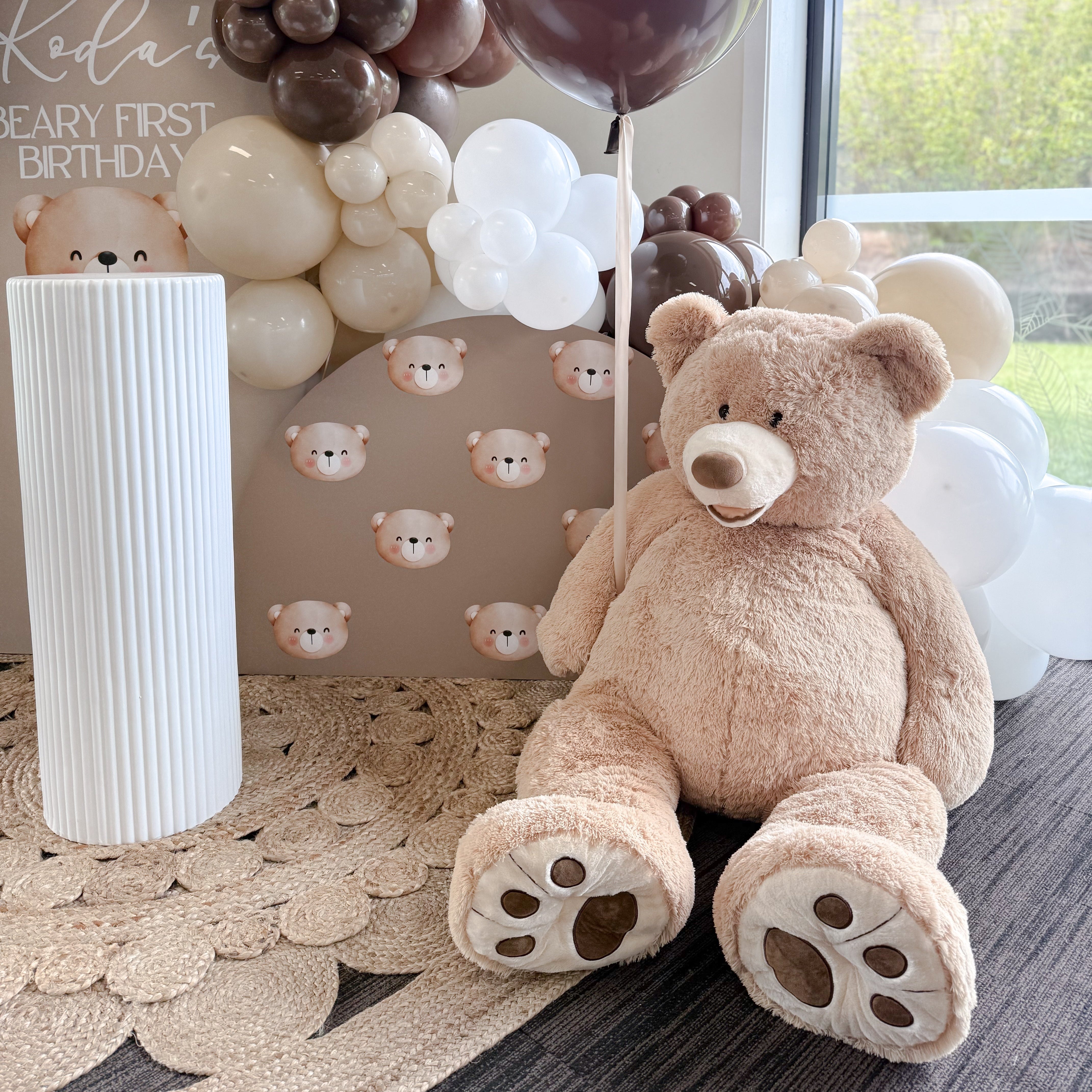 eddy bear themed first birthday backdrop with balloons and signage
