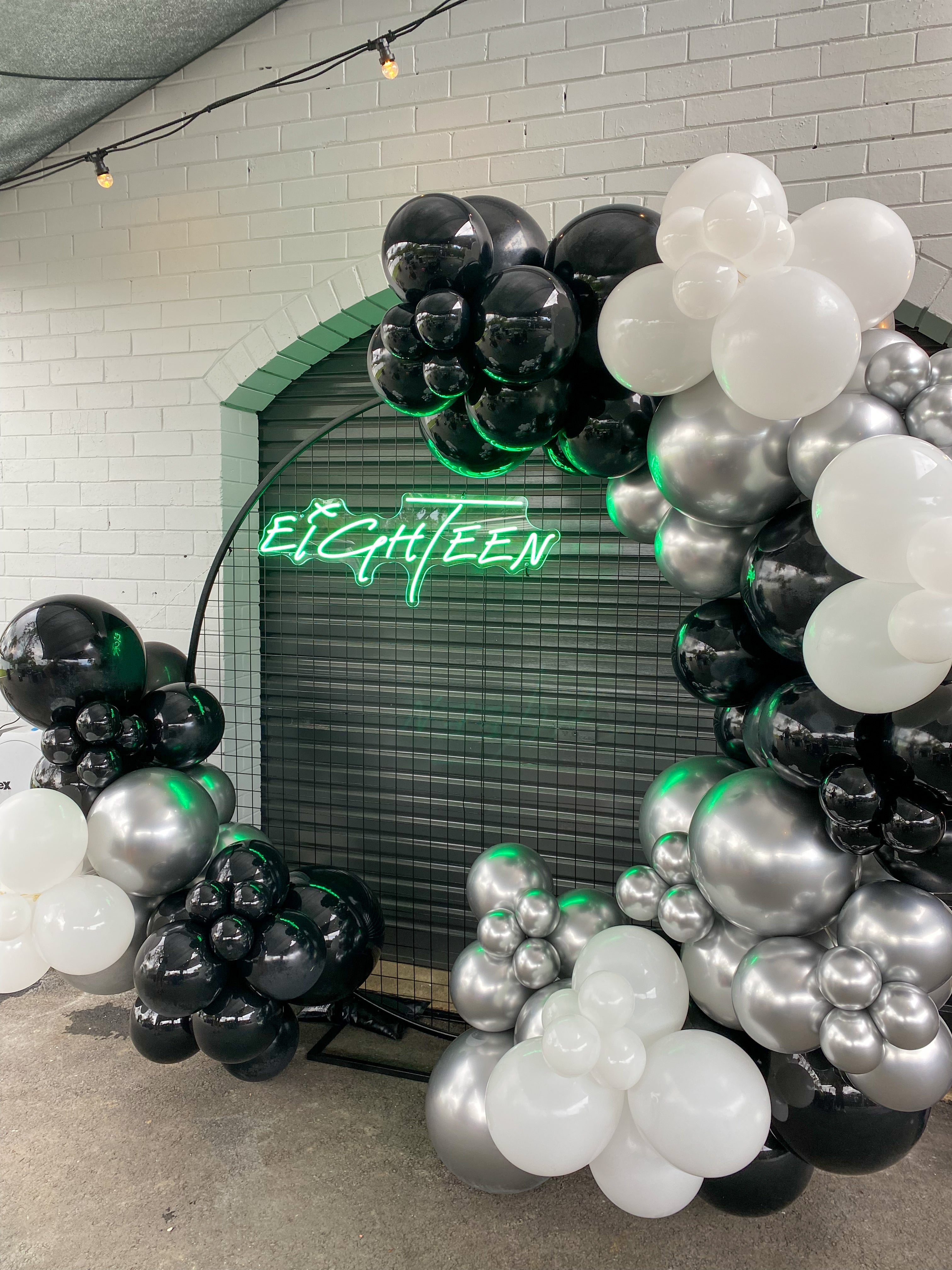 Gold Coast birthday party balloon hoop decor setup with black, silver and white balloons